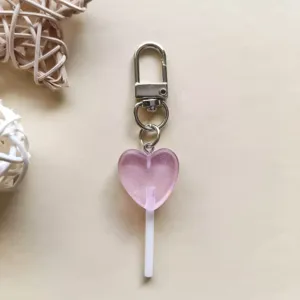 Dettaglio del grazioso portachiavi a forma di lecca-lecca a cuore rosa traslucido con glitter.