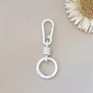 White zinc alloy spring keychain detail shot, compact metal carabiner hardware accessory.
