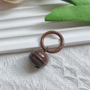 Detailed close-up of brown metal bell pendant with spring ring charm for DIY bag accessories.