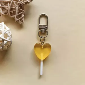 Vista dettagliata portachiavi caramella a cuore, ciondolo resina gialla e gancio a moschettone.