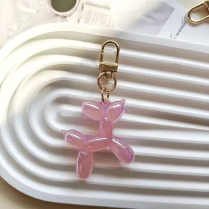 Detailed close-up shot of a cute pink jelly balloon dog keychain charm on a white ribbed tray.