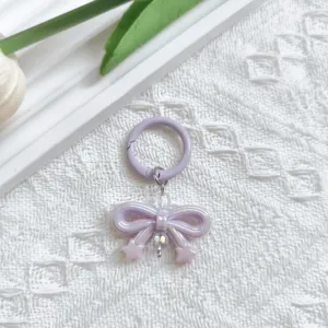 Purple bow keychain detail shot, cute bag charm pendant, acrylic and metal accessories.