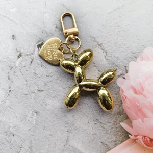 Gold balloon dog keychain detail, metal puppy charm pendant for bags and car keys.