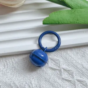Close-up of blue metal painted bell keychain pendant, DIY bag charm jewelry accessory detail.