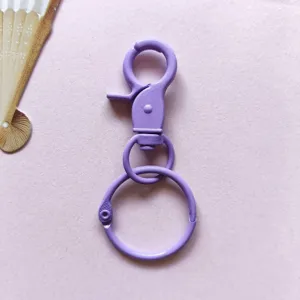 Dettaglio moschettone metallo viola portachiavi, gancio colorato per charm borsa fai da te.