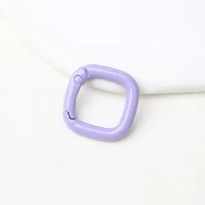 Detailopname van een lichte paarse metalen vierkante veergesp voor tasaccessoires en sleutelhangers.