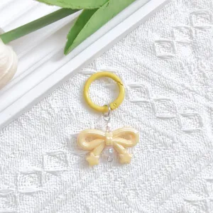 Cute yellow bow keychain with metal spring ring, glossy bag pendant charm accessory.