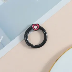 Primer plano detallado del cierre de anillo de resorte de metal negro con un dije de corazón rosa.