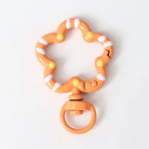 Orange enamel flower keychain clip detail, cute DIY jewelry accessory charm, smooth metal surface.