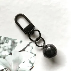 Dettaglio del portachiavi in metallo nero con moschettore girevole e campanello da 14mm.