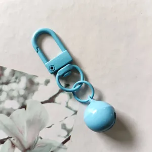 Dettaglio portachiavi in metallo azzurro con campanello e gancio rotante per borse DIY.
