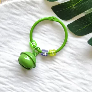 Nahaufnahme des grüne Metall Ring Schlüsselanhängers mit Glocke und Buchstabenperlen.