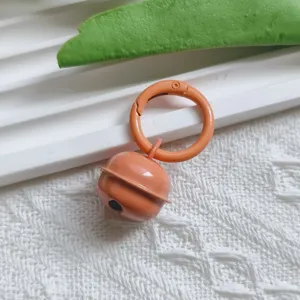 Close-up of orange metal candy bell pendant with spring clasp for DIY keychain craft details.