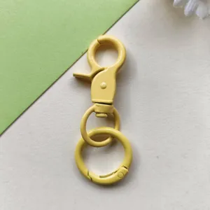 Dettaglio hardware metallico per portachiavi con moschettone giallo per accessori borse.