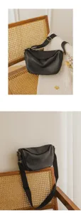 Black genuine leather shoulder crossbody dumpling bag lifestyle detail view on rattan chair.