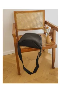Black leather crescent shoulder bag detail shot, featuring soft genuine leather texture and wide strap.
