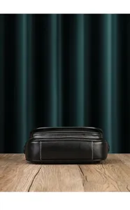Close-up detail of a black leather crossbody bag featuring neat stitching and soft construction.