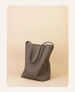 Close-up detail of taupe genuine leather bucket bag, minimalist tote, premium texture and stitching.