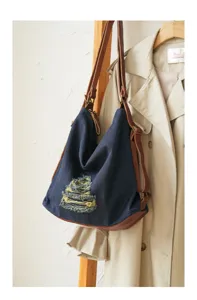 Detailed view of slouchy denim and brown leather multi-way backpack and shoulder bag.