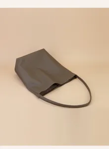 Detailed view of minimalist leather shoulder bag, soft taupe leather texture, slim strap.