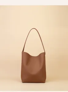 Brown leather minimalist shoulder bag detail showing smooth texture and curved handle.