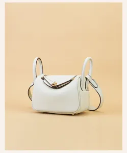 Close-up detail of premium leather mini handbag with gold hardware and dual top handles.