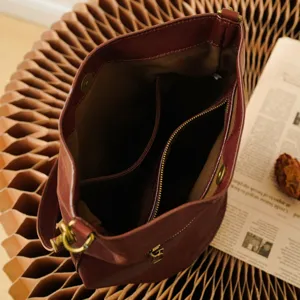 Genuine leather bucket bag interior view, large capacity shoulder handbag with brass hardware.