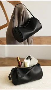 Detail view of black cylindrical soft leather shoulder bag showing interior capacity and zipper.
