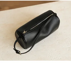 Detailed view of the black cylindrical soft leather crossbody bag with metal zipper and fine strap.