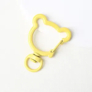 Close-up of yellow bear-shaped swivel spring snap hook, durable alloy DIY keychain accessory.