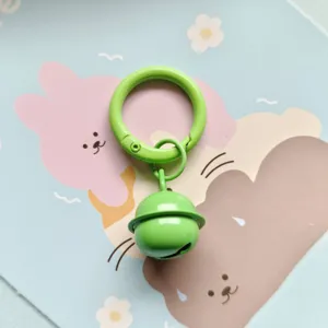 Candy color metal spring buckle and bell pendant, minimalist key ring and bag decoration detail.