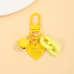 Gros plan sur les détails de la chaîne en acrylique jaune et du porte-clés cœur en métal.