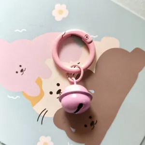 Cute pink metal spring ring keychain with a small bell charm for stylish bags and keys.