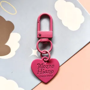 Close-up of pink painted metal heart keychain pendant, cute candy color DIY accessory.