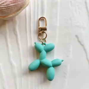 Cute candy color balloon dog keychain close up, rubber charm pendant for bags and keys.