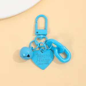 Détail en gros plan du porte-clés cœur en alliage bleu vif avec cloche et chaîne.