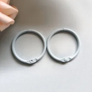 Close-up detail of light gray metal binder rings, smooth painted surface for DIY crafts.
