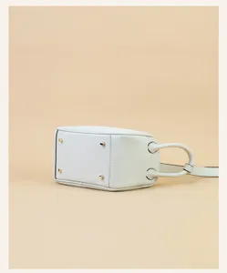 Detailed view of the bottom and side of a mini leather crossbody shoulder bag with gold tone feet.