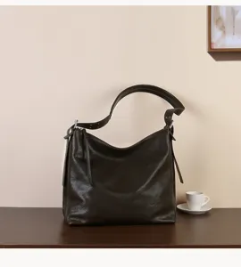 Close-up detail of dark brown leather hobo shoulder bag showcasing soft texture and metal hardware.