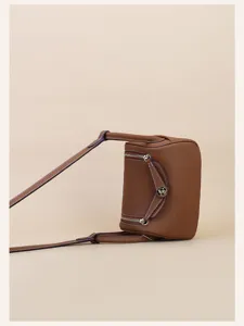 Mini brown leather crossbody handbag with shoulder strap and metal hardware details for women
