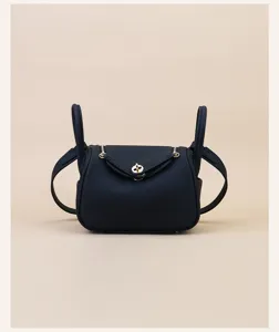 Detail view of dark blue leather mini handbag with gold hardware and side handle design.