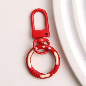 Rode metalen karabijnhaak sleutelhanger detailweergave met glanzende verf en leuk hangertje.