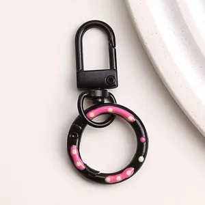 Gedetailleerd overzicht van de zwarte legering donut sleutelhangerring met roze stippen.