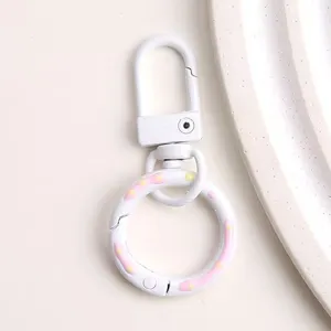 Gedetailleerd overzicht van witte legering sleutelhanger met roze en gele stippen veerring.