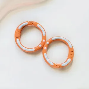 Detailed close-up shot of orange donut spring rings with colorful enamel details for DIY.
