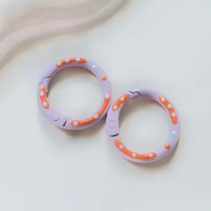 Metal donut spring ring detail showing purple enamel finish with orange and white dots.