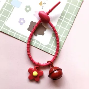 Close up of red silicone cable tie charm with flower and bell pendant for DIY craft decoration.