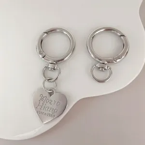 Detail view of silver metal keychain spring rings with heart pendant and rotating clasp hardware.
