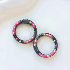 Close-up detail of black metal spring rings with colorful drip oil polka dot DIY jewelry accessories.