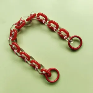 Dettaglio catena in acrilico con maglie rosse e trasparenti e anelli in metallo per borse fai da te.